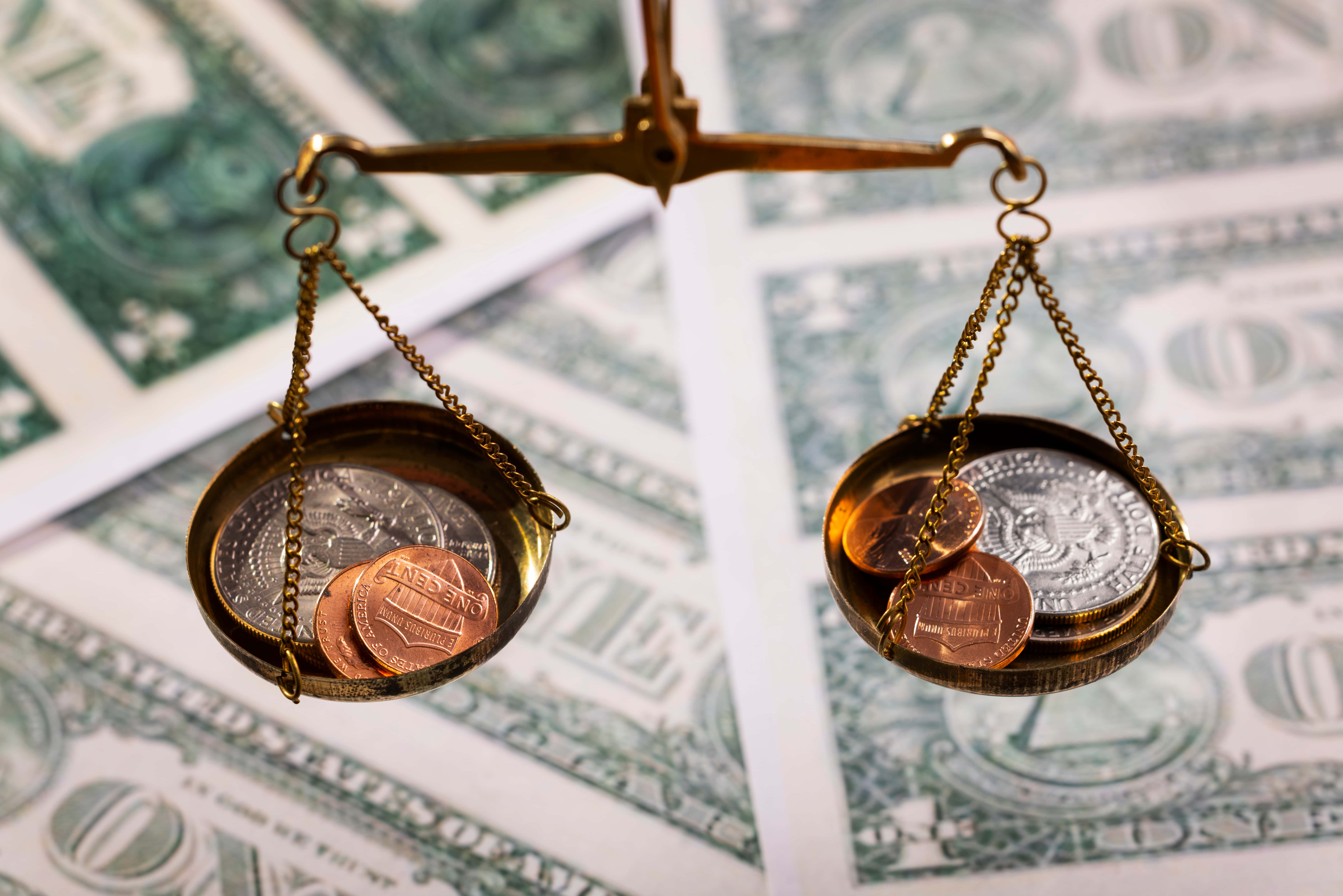 A legal scale with gold coins and dollar bills. - Jerone Toledo Holding